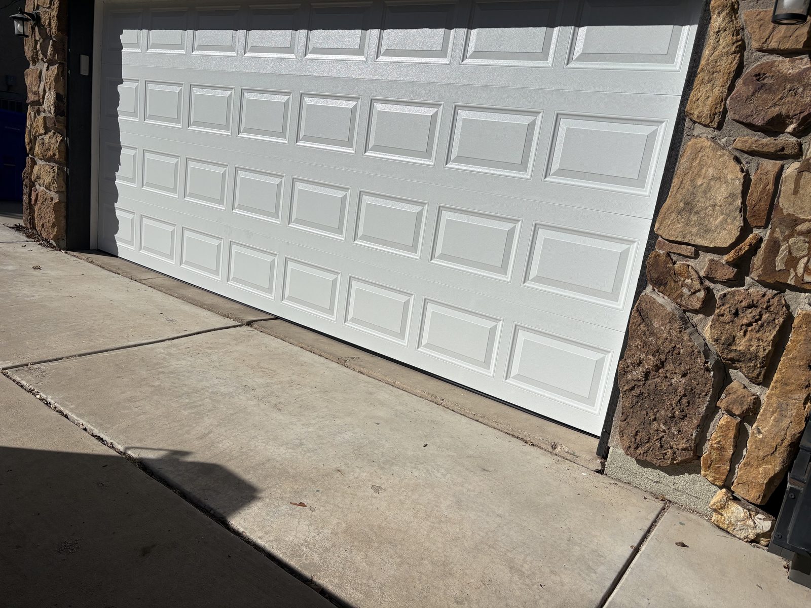 White raised panel garage door replacement with stone facade